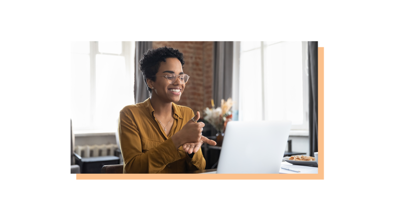 A woman expressing accomplishment in front of a laptop.