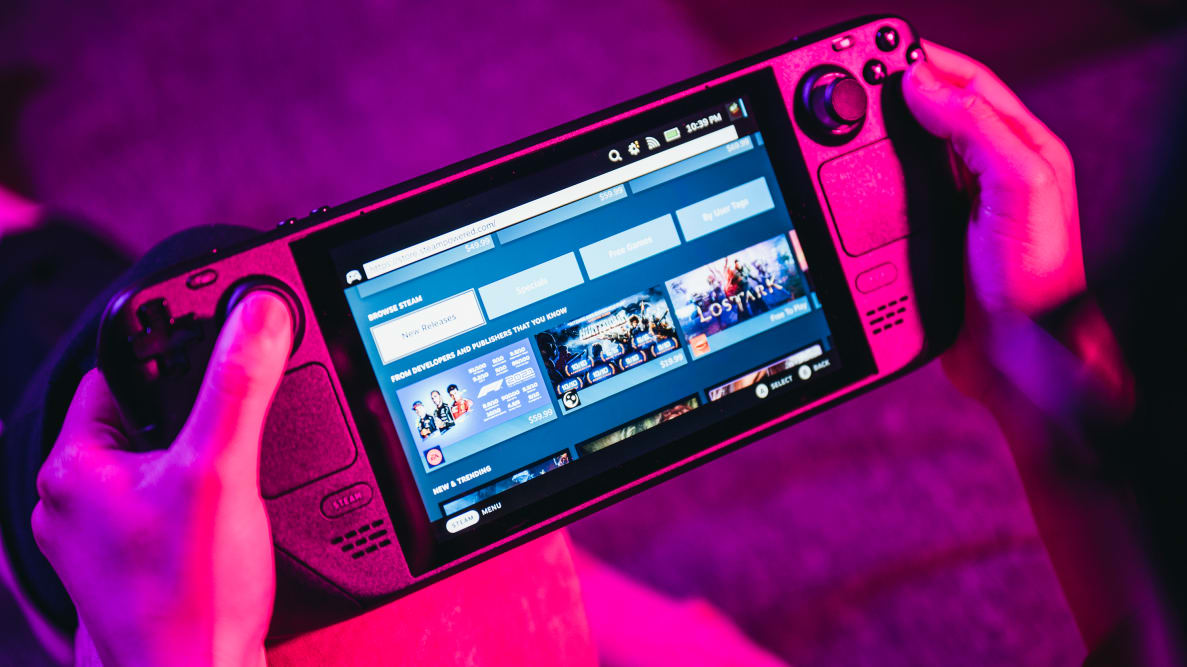 A person holding a handheld gaming device, soft pink-purple lighting