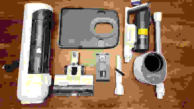 Separated vacuum parts lay on a brown wooden floor