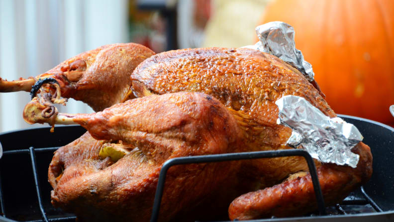 A perfectly browned turkey sits in a roasting pan.