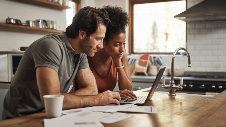 Couple sitting at kitchen table reviewing bills.