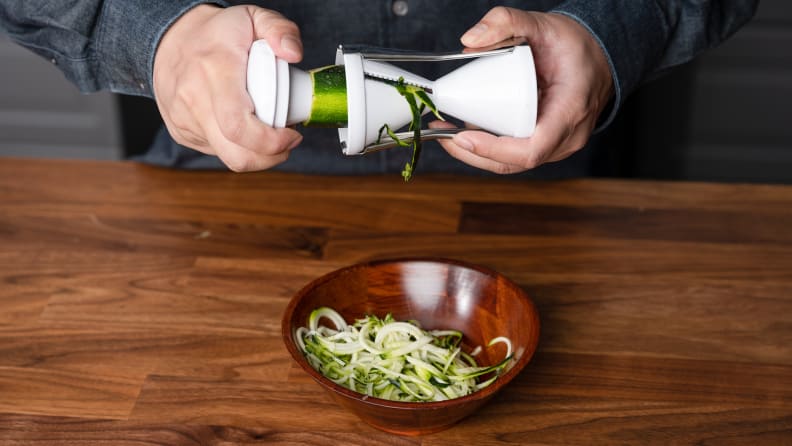 A zucchini is cut into spirals using a Veggetti spiralizer