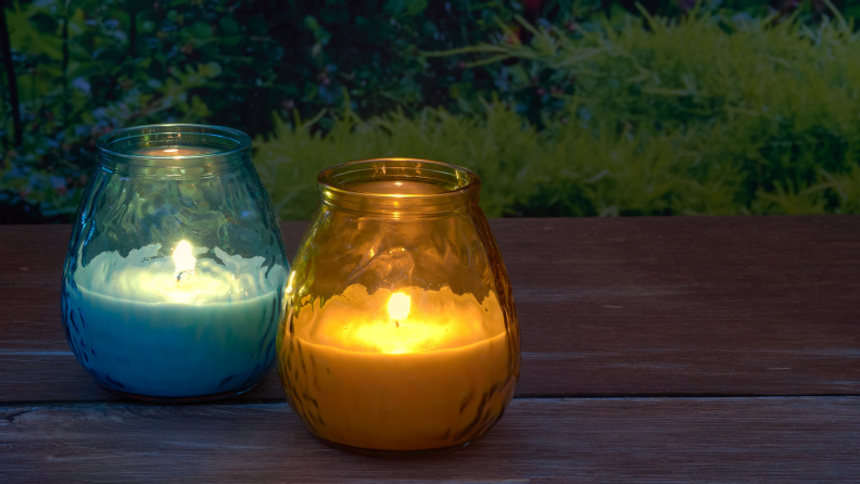 Two decorative citronella candles, one blue and one orange, sitting on a table