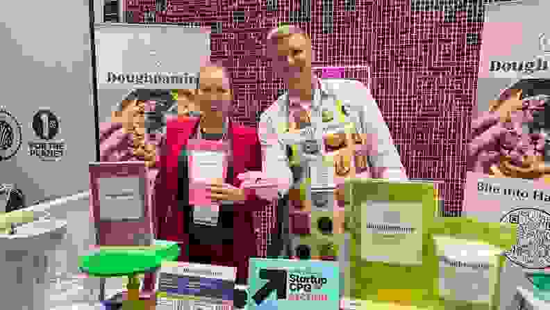 Two people holding Doughpamine products in front of a display