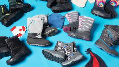 10 pairs of children's winter boots laying on a blue background.