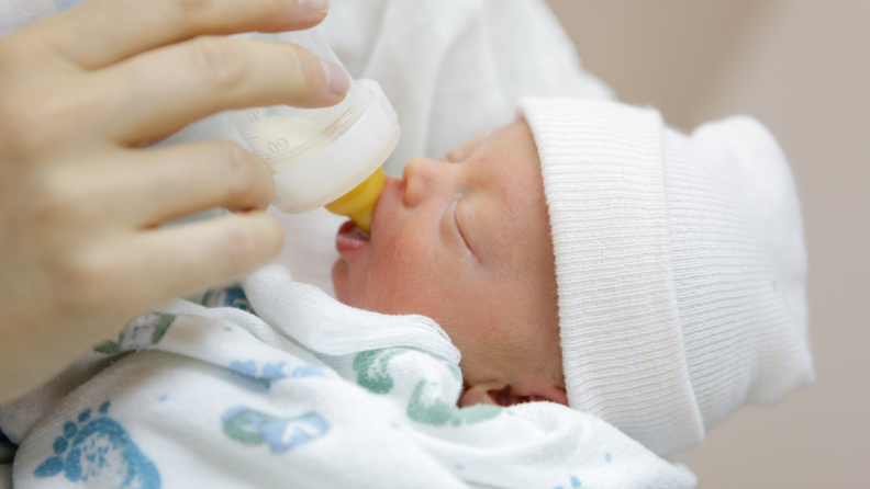 Newborn baby drinks baby formula from bottle