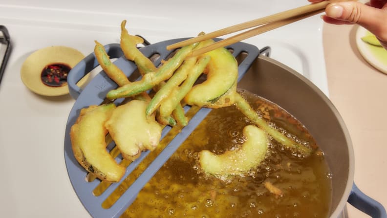 A Perfect Pot filled with oil, vegatable tempura sitting on the Fry Deck attached to the left side on the pot, with chopsticks grabbing a piece of green bean tempura.