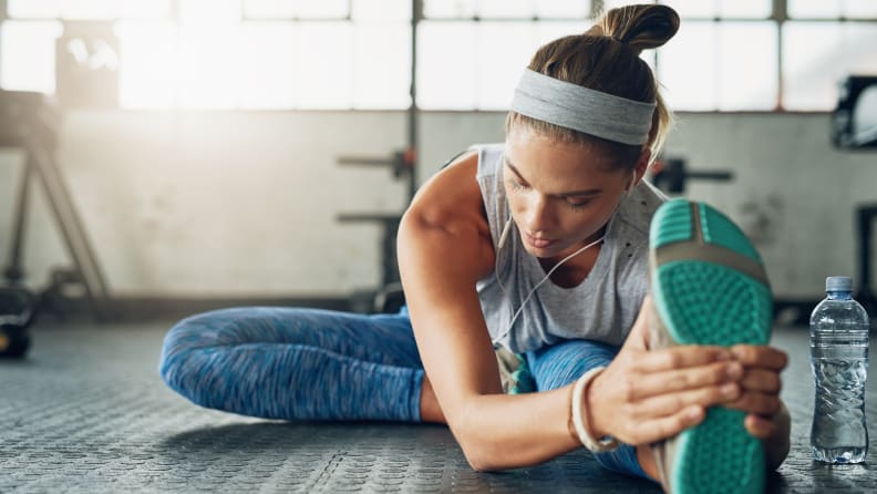 A woman stretching her hamstrings at the gym