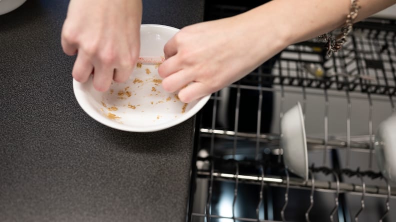 A person measures food stains on a white bowl with a measuring tape