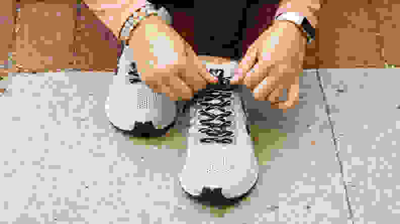 A person ties the shoelaces of running shoes.