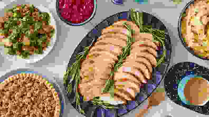 A sliced turkey surrounded by side dishes on a table
