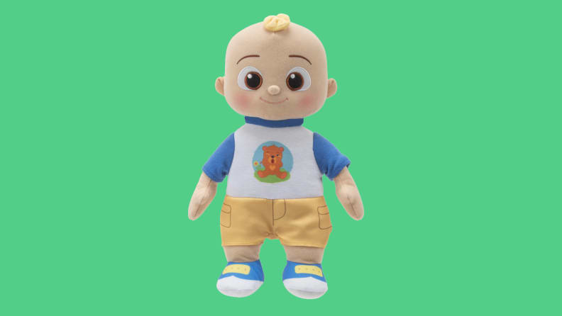 A Cocomelon Boo Boo JJ Doll shown with shorts and a white and blue t-shirt.