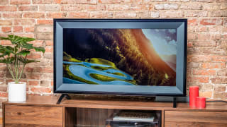 An OLED TV set sits on top of a credenza in a living room.