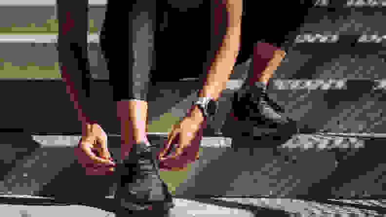 Hands of an anonymous runner tying shoelaces on sneakers.