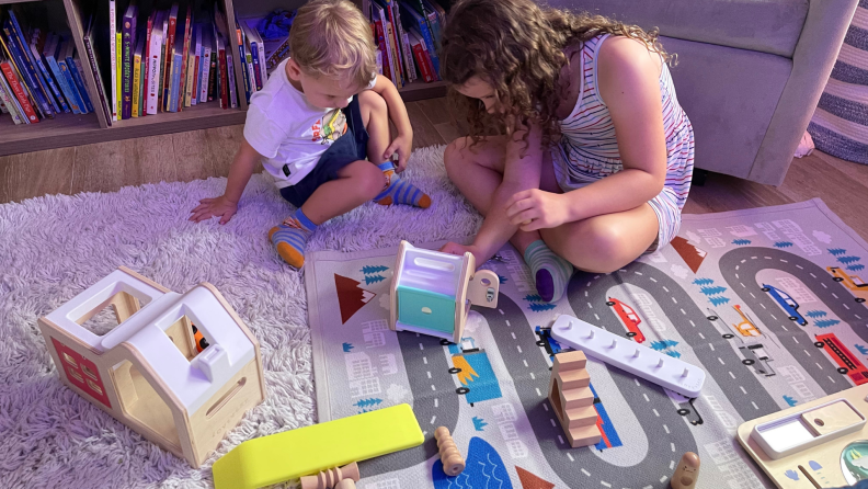 Two kids sitting on the floor, playing with toys