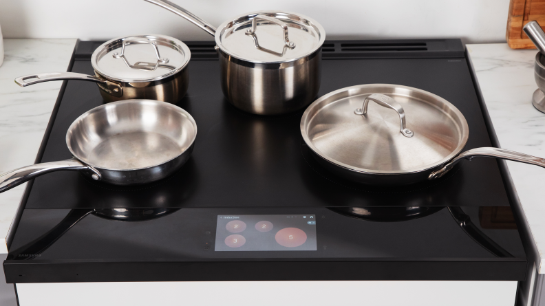 Four pots pots and pans sit on the cooktop of the Samsung Bespoke NSI6DB990012AA Induction Range