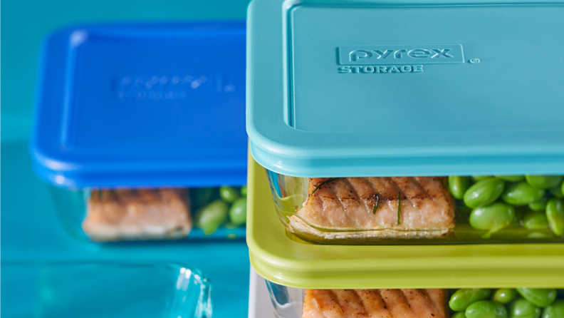 An image of several Pyrex storage containers stacked together on top of one another, all with blue or green lids.