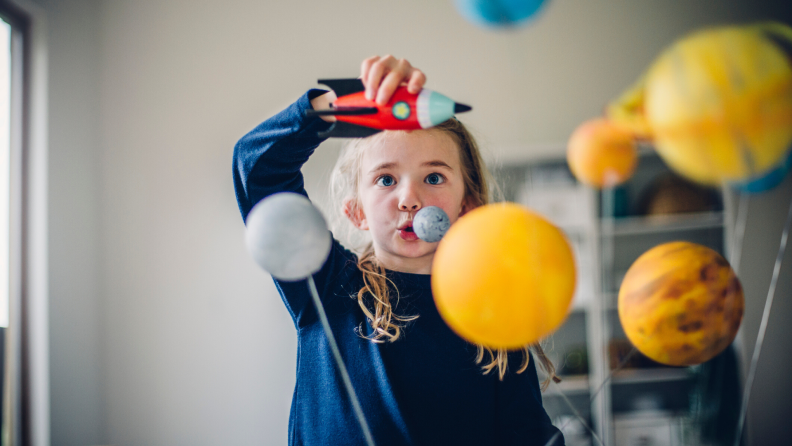Girl playing with a set of planets and spaceship