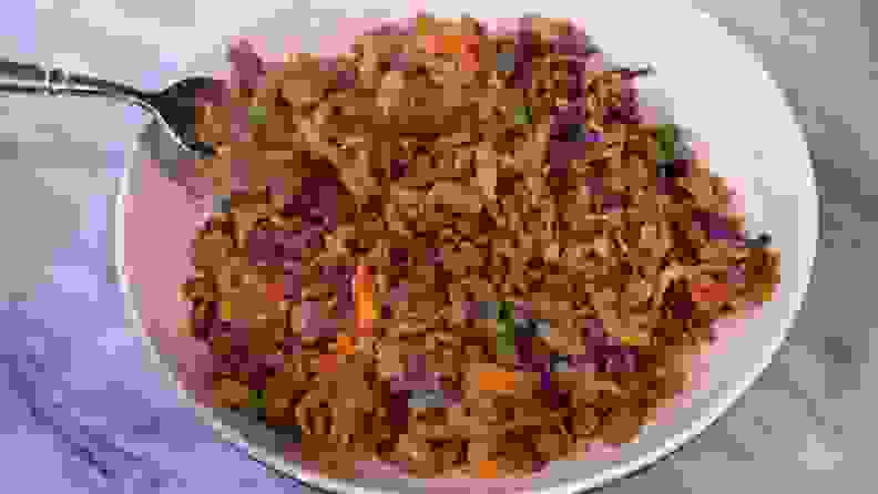 Cooked vegetables and rice inside of white bowl on countertop surface.