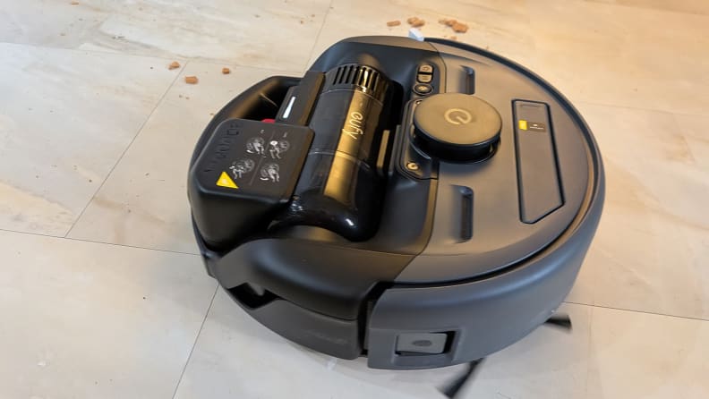A black robot vacuum on a tile floor