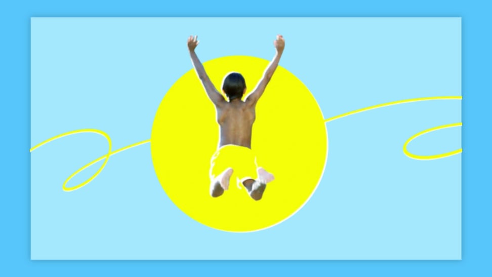 A boy jumps into the sun wearing yellow swim trunks