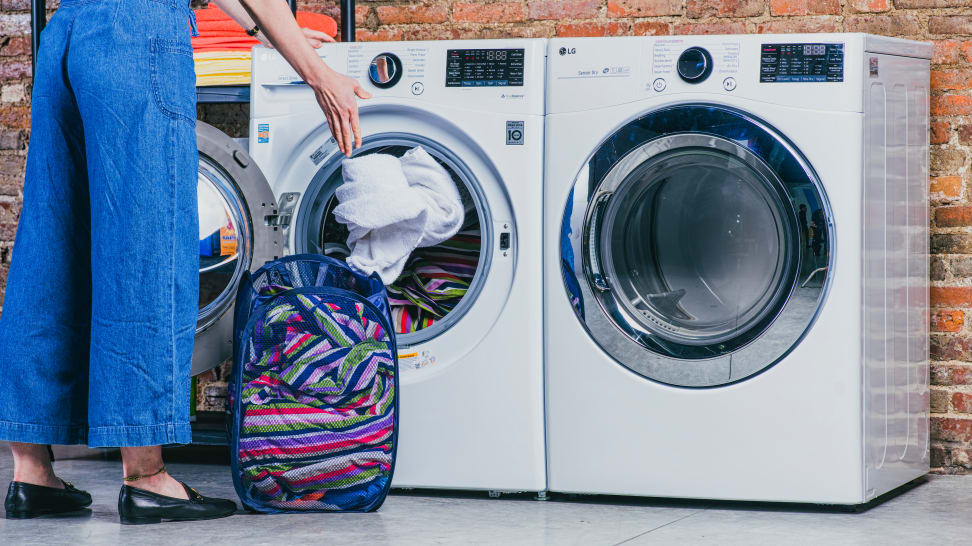 A woman loading laundry into an LG front load washing machine.