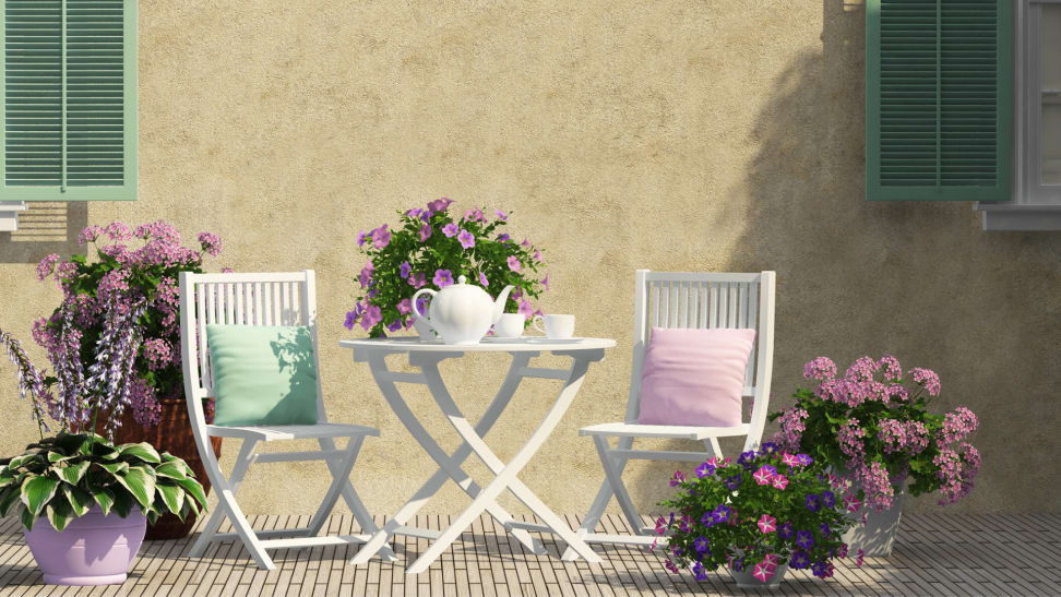 A white bistro set with pink flowers and a tea set.