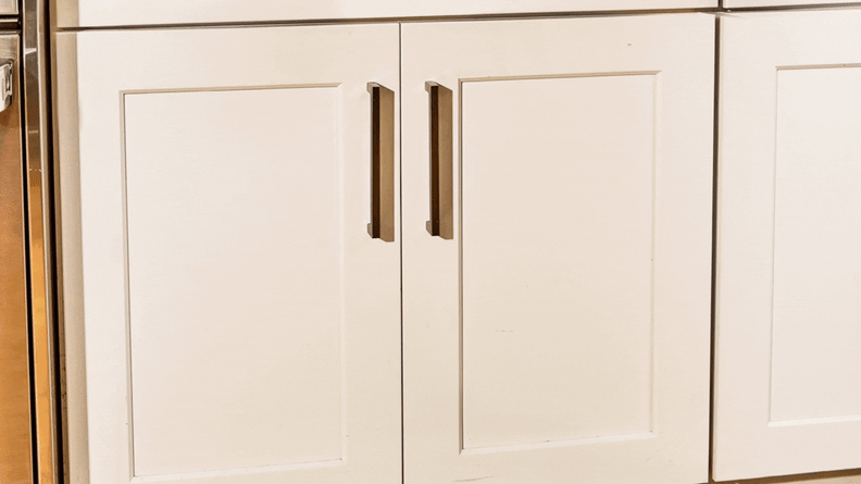 A gif of a person opening cabinet doors and Caraway cookware is stored inside the cabinet.