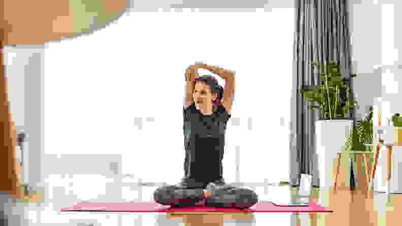 A woman stretching her arms in an overhead stretch.