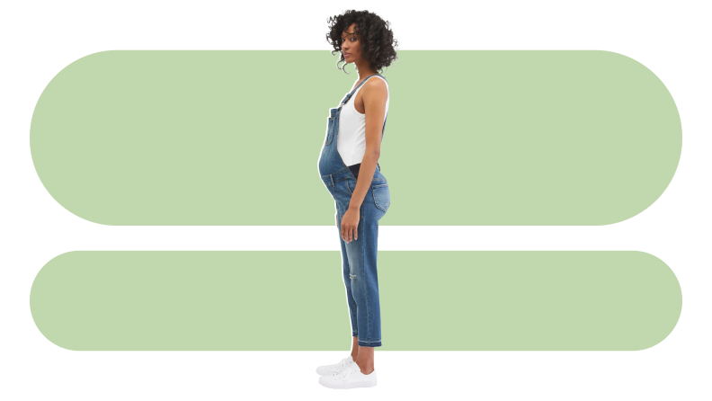 Product shot of of pregnant person wearing the Motherhood Maternity Side Panel Letdown Hem Maternity Overalls.