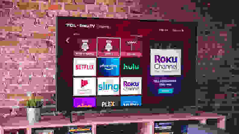 The 2020 TCL 6-Series displaying the Roku smart platform home screen in a living room setting