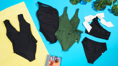 Four Summersalt swimsuits on a blue and yellow backdrop: two black one-piece swimsuits, one green one-piece, and one black bikini with a white bow.