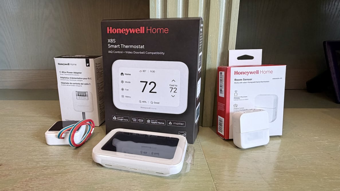 A Honeywell smart thermostat with three product boxes and accessories on a beige counter.