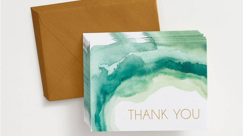 A set of thank you notes with gold font and emerald green watercolors.