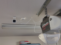 A security camera hangs next to a garage door opener