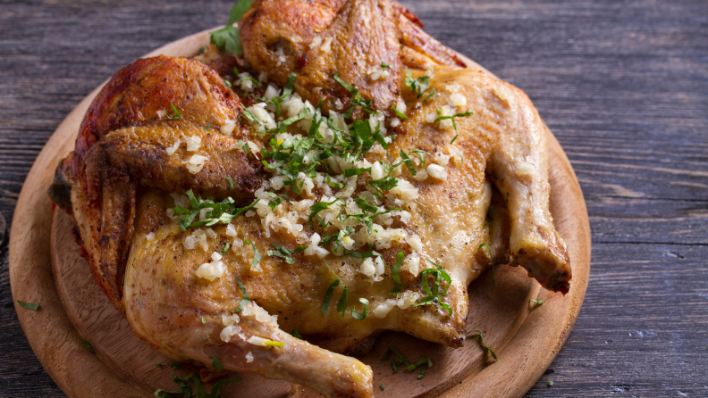 A spatchcocked turkey on a round cutting board.