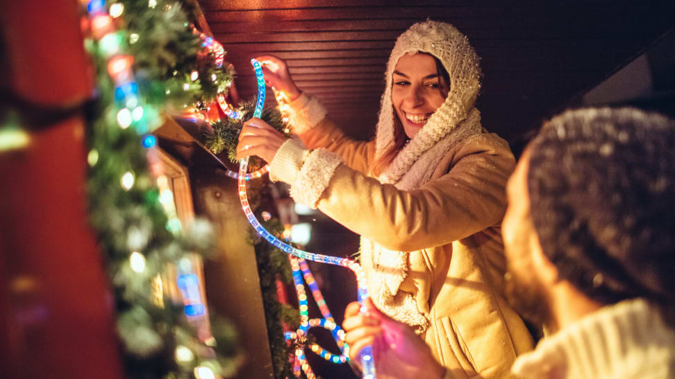 Two people hanging Christmas lights outside
