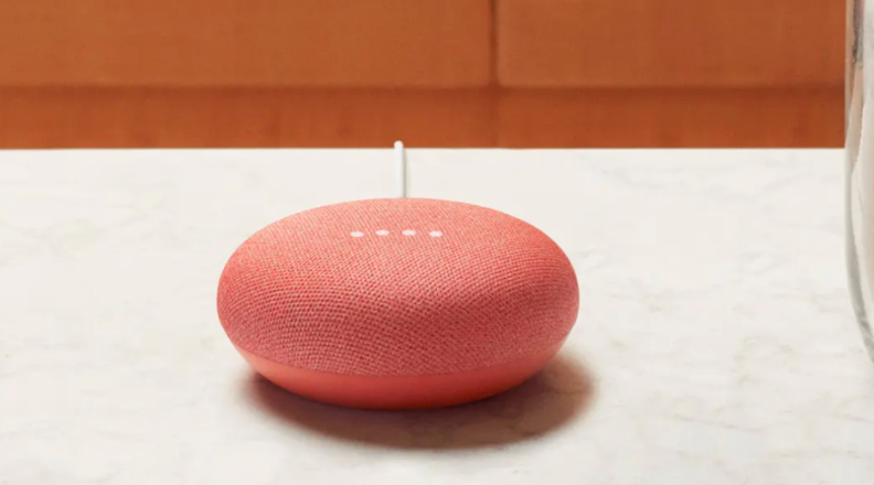 A Google Home Mini smart speaker sits on a countertop.