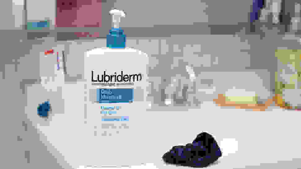 A large bottle of body lotion standing on the side of a sink.