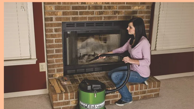 Woman using vacuum to clean fireplace.