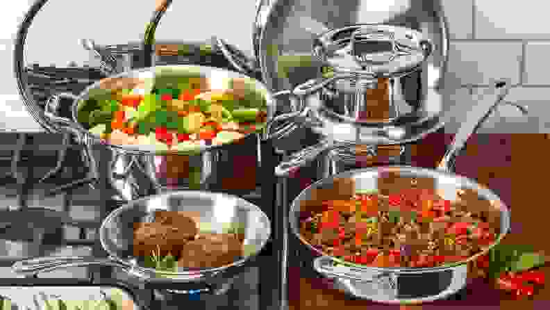 Pot with assorted vegetables, frying pan with two cooked steaks and larger frying pan with more assorted vegetables on and next to stove top.