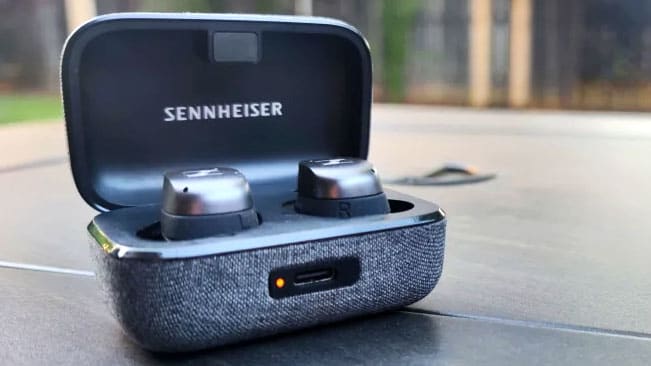 The graphite Sennheiser Momentum True Wireless 3 sit in their gray fabric case with the lid open.