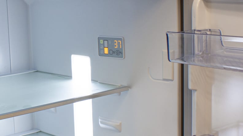 A close-up of the fridge's controls, which consist of a small rectangular touchpad and an orange digital readout, located on the right wall of the fridge.