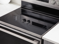 A close-up photo of an electric range highlighting the electric cooktop and the oven control knobs.