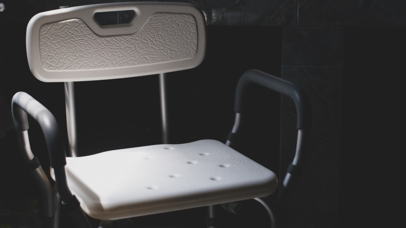 A plastic adjustable chair sits in a shower.