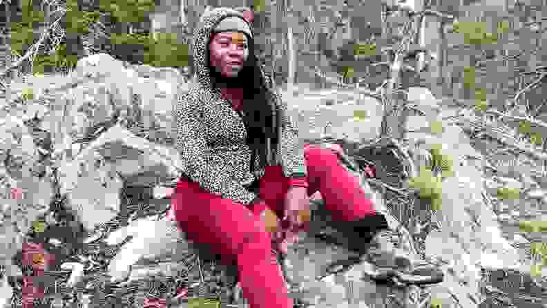 A model poses outdoors wearing a knit hat, a leopard-print hoodie, and red thermal pants.