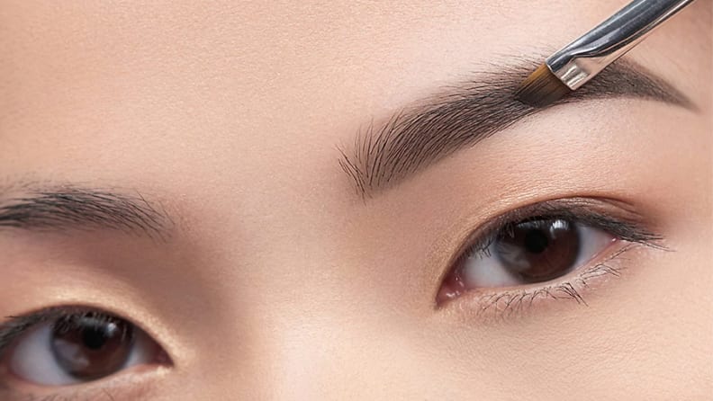 A woman fills in her brows with the Anastasia Beverly Hills Brow Powder Duo.