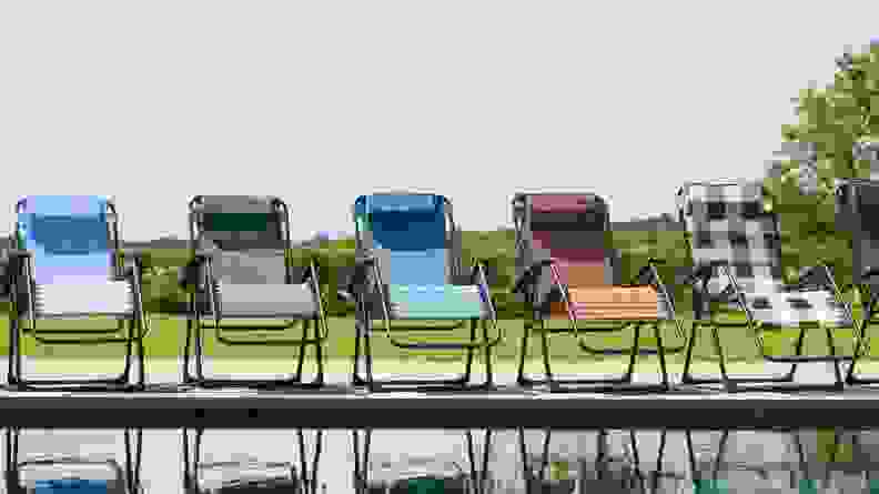 Five patio chairs sitting alongside a pool.