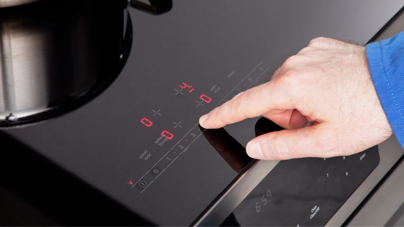 Person using finger to operate the control panel on the Bosch HII8057U 800 Series Induction Slide-in Range.