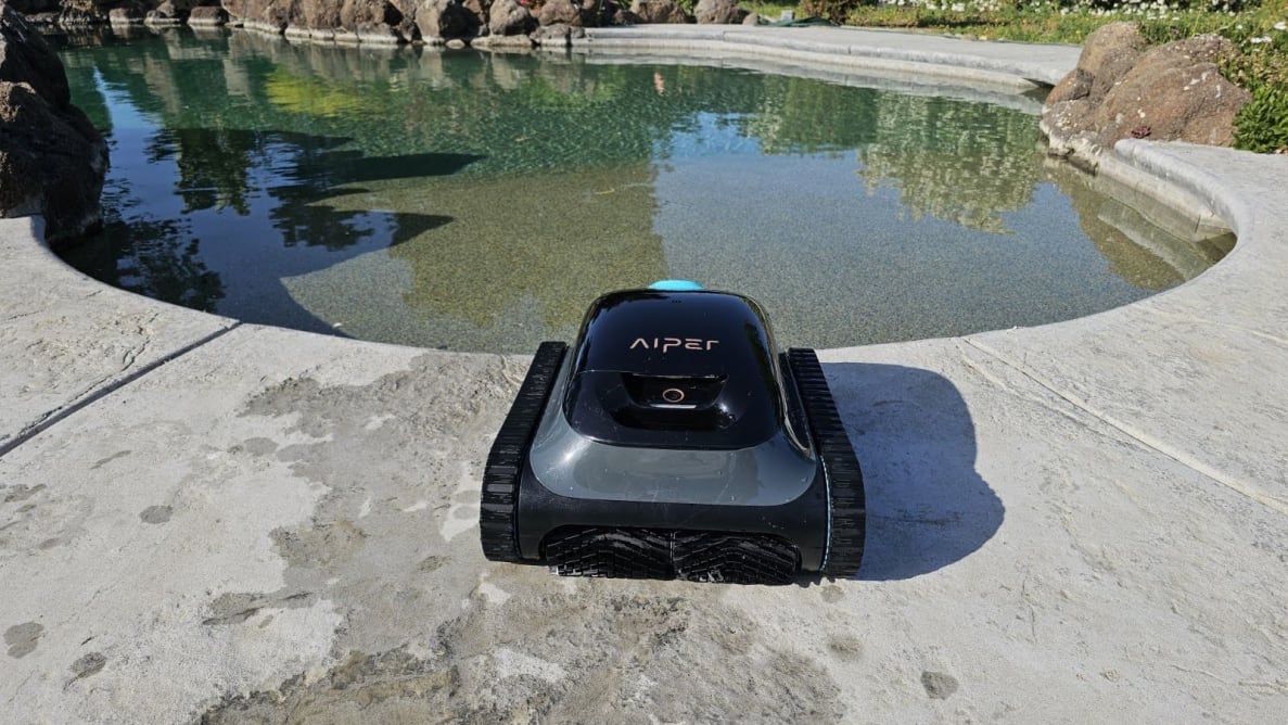The Aiper Scuba S1 pool cleaner on a concrete pool deck outdoors.